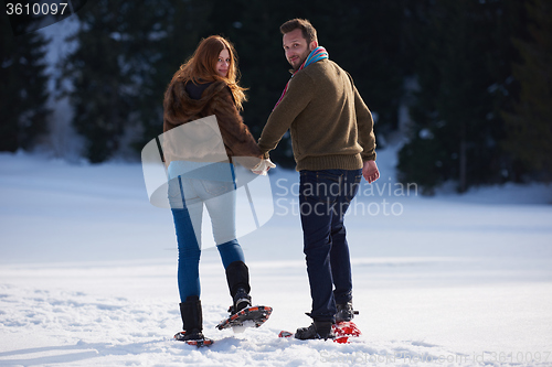 Image of couple having fun and walking in snow shoes