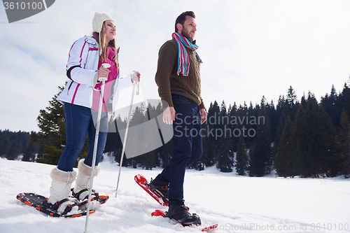 Image of couple having fun and walking in snow shoes