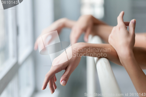 Image of The  hands of two classic ballet dancers at barre