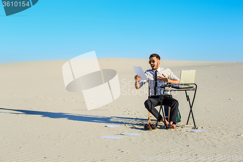 Image of Businessman using  laptop in a desert