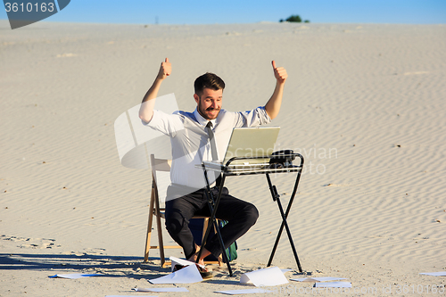 Image of Businessman using  laptop in a desert