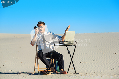 Image of Businessman using  laptop in a desert