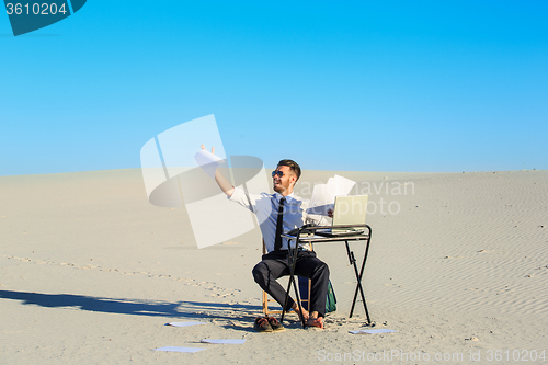 Image of Businessman using  laptop in a desert