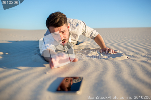 Image of Poor signal. businessman searching for mobile phone signal in desert