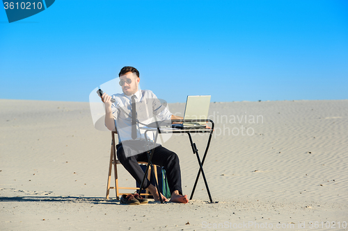 Image of Businessman using  laptop in a desert