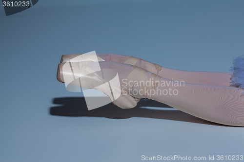 Image of legs of the ballerina in ballet  pointes on blue background