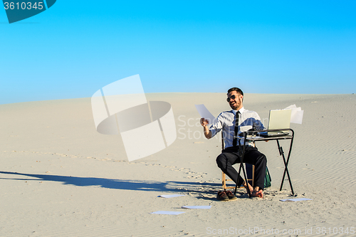 Image of Businessman using  laptop in a desert