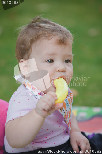 Image of Baby, less than a year old   playing with  toy banana 