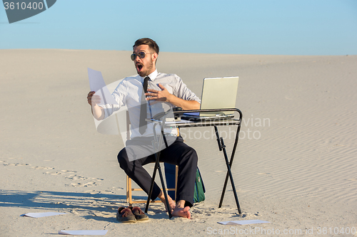 Image of Businessman using  laptop in a desert