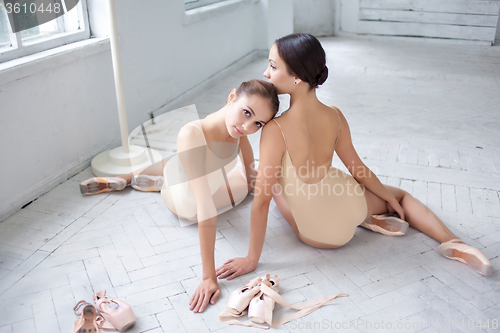 Image of The two classic ballet dancers posing on white wooden floor