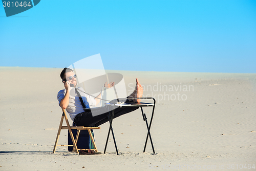 Image of Businessman using  laptop in a desert