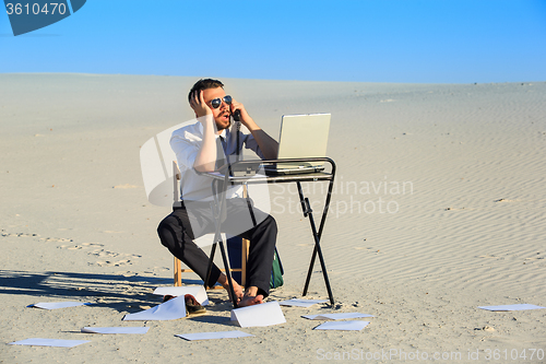 Image of Businessman using  laptop in a desert