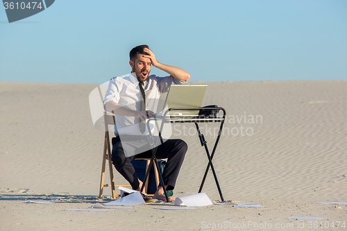 Image of Businessman using  laptop in a desert