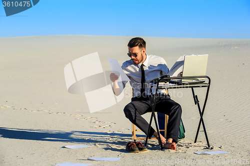 Image of Businessman using  laptop in a desert