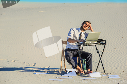 Image of Businessman using  laptop in a desert