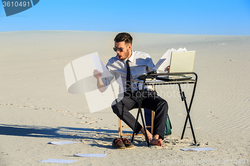 Image of Businessman using  laptop in a desert