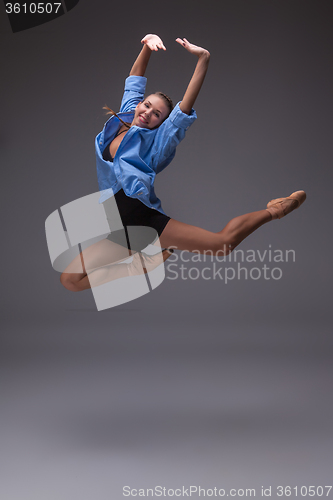 Image of Young beautiful modern style dancer jumping in a studio background
