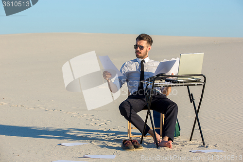 Image of Businessman using  laptop in a desert