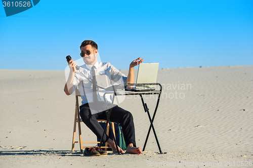 Image of Businessman using  laptop in a desert