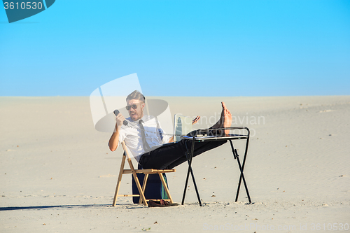 Image of Businessman using  laptop in a desert