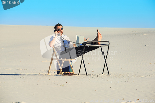 Image of Businessman using  laptop in a desert