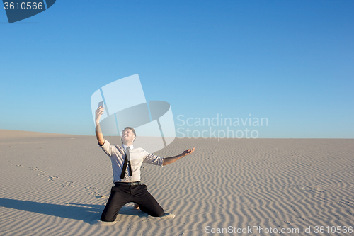 Image of Poor signal. businessman searching for mobile phone signal in desert