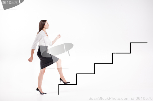 Image of Young businesswoman walking up on stairs