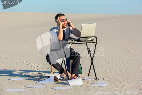 Image of Businessman using  laptop in a desert