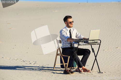 Image of Businessman using  laptop in a desert