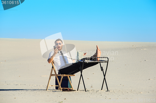 Image of Businessman using  laptop in a desert