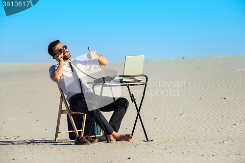 Image of Businessman using  laptop in a desert