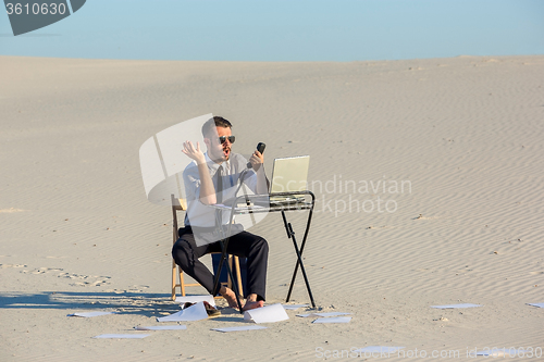 Image of Businessman using  laptop in a desert