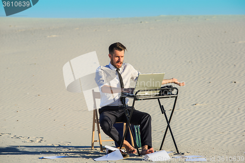 Image of Businessman using  laptop in a desert