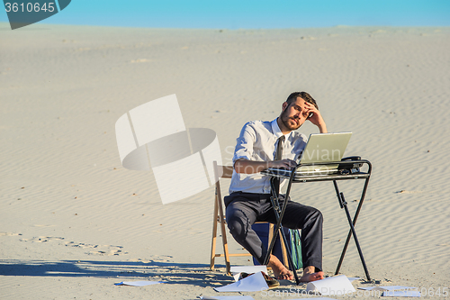 Image of Businessman using  laptop in a desert