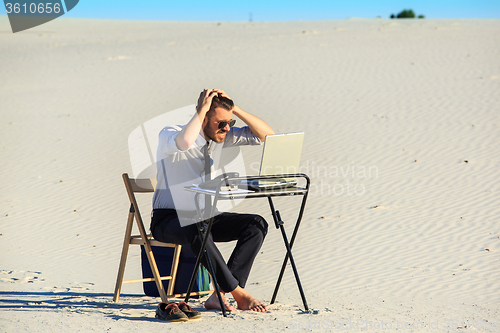 Image of Businessman using  laptop in a desert