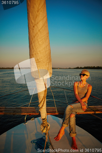 Image of Woman traveling by boat at sunset