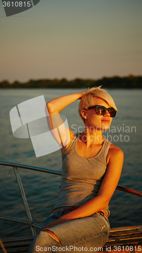 Image of Woman traveling by boat at sunset
