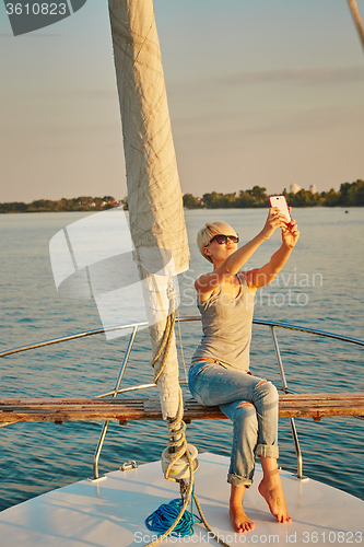 Image of Pretty young female tourist makes selfie on yacht