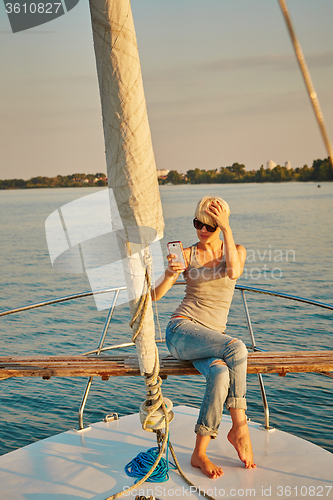 Image of Pretty young female tourist makes selfie on yacht