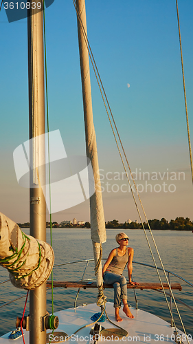 Image of Woman traveling by boat at sunset