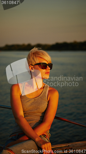 Image of Woman traveling by boat at sunset