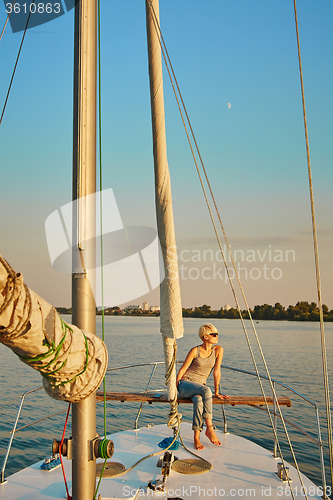 Image of Woman traveling by boat at sunset