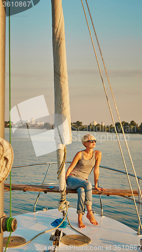 Image of Woman traveling by boat at sunset