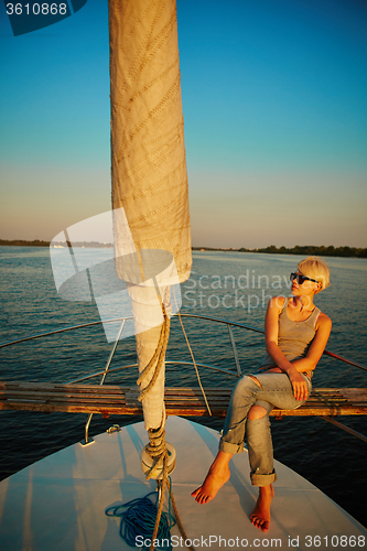 Image of Woman traveling by boat at sunset