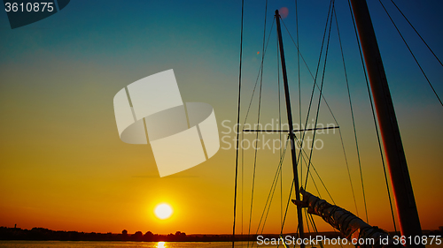 Image of Sail boat gliding in sea at sunset