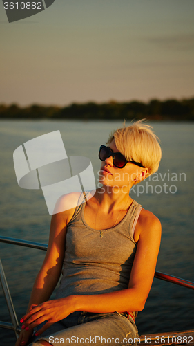 Image of Woman traveling by boat at sunset