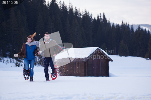 Image of couple having fun and walking in snow shoes