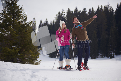 Image of couple having fun and walking in snow shoes