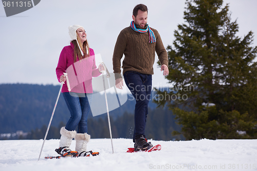 Image of couple having fun and walking in snow shoes