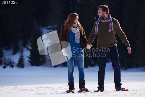 Image of couple having fun and walking in snow shoes